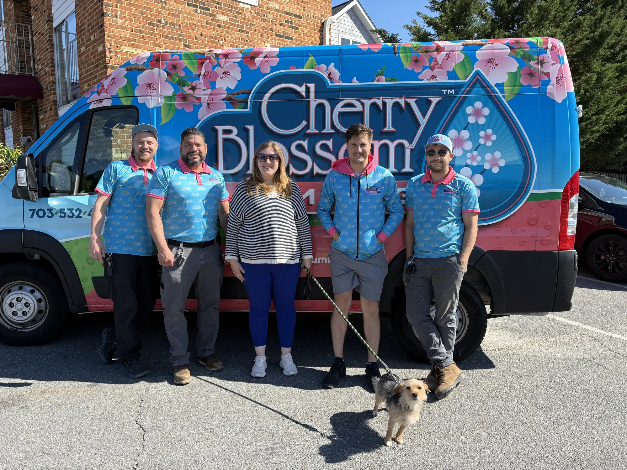 Cherry Blossom Plumbing crew and mascot dog posing in front of a branded service van