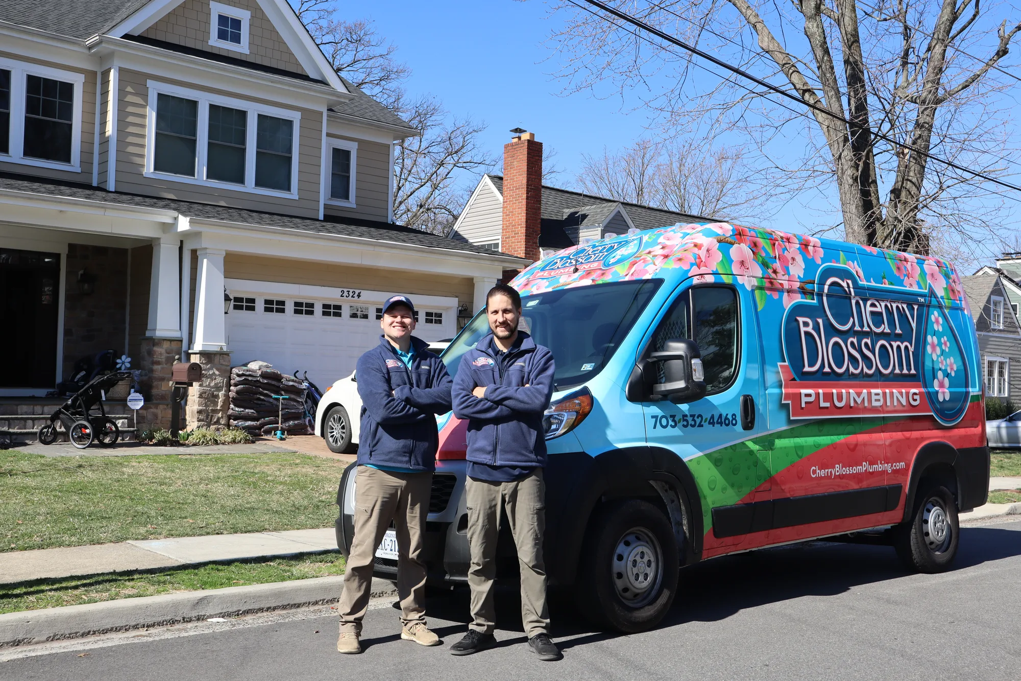 Technicians standing proudly with a branded service van