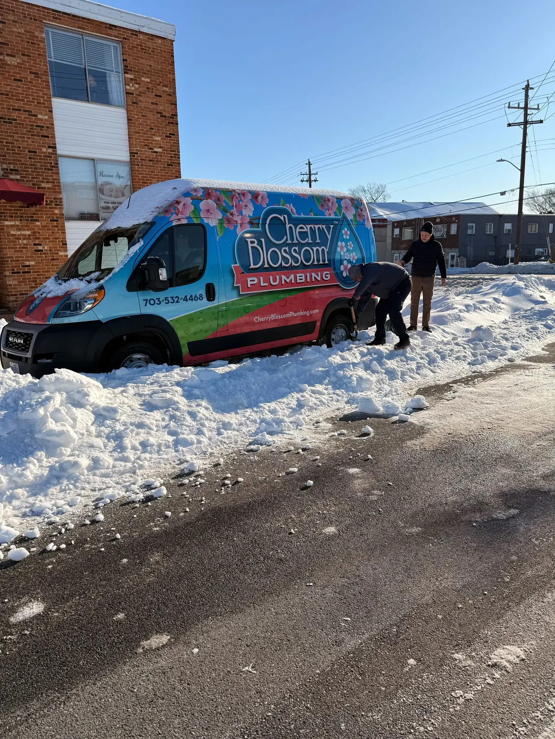 Technicians shoveling a service van out of snow